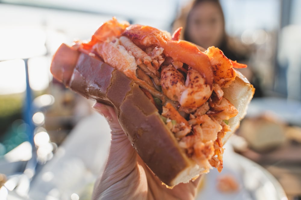 People eating a Lobster Roll at the Hampton Beach Seafood Festival